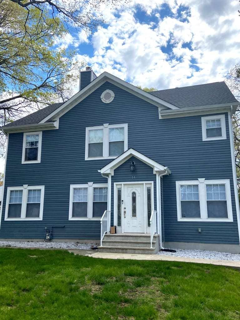 Two-story blue home with white trim and newly installed vinyl siding exterior renovation.