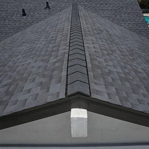Close-up of roof ridge cap shingles and chimney flashing detail by Bluebeam Group roofing in Orange County NJ